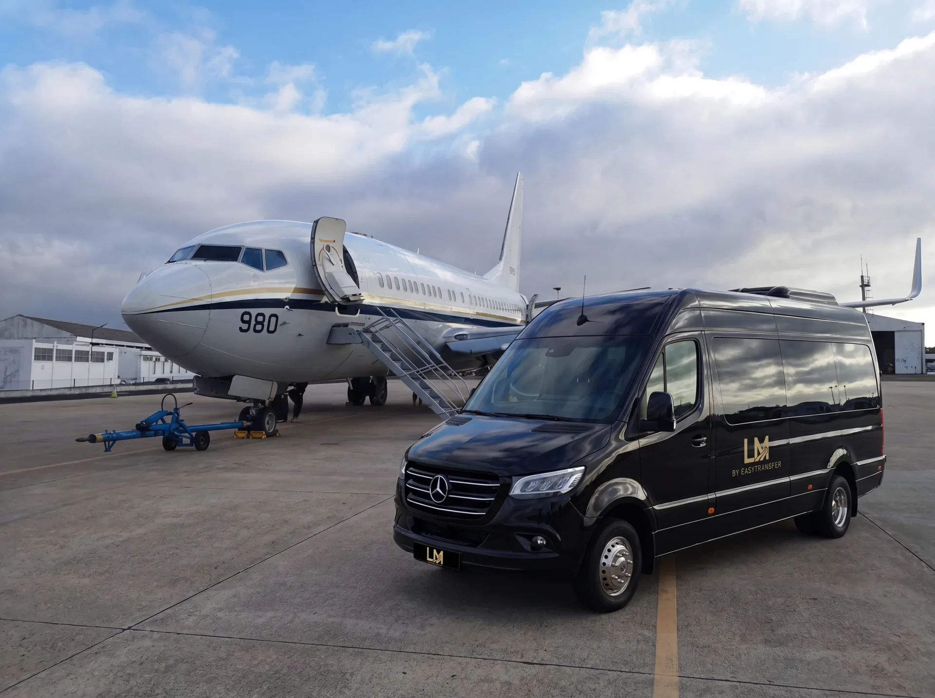 LuxMotion Sprinter van beside a private jet on the apron