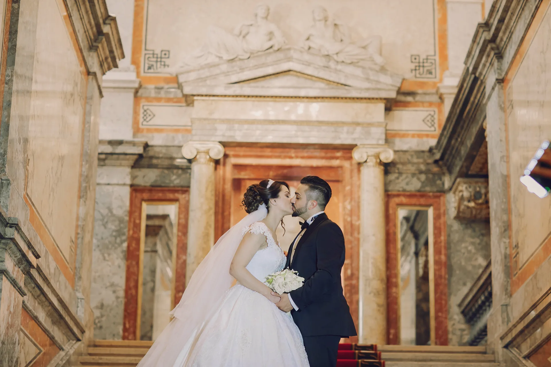 Bride and groom kissing inside ornate church